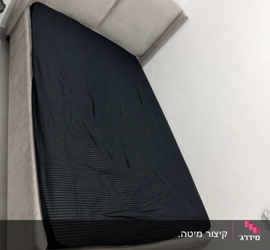 מיטה עם מזרן שחור בחדר שינה